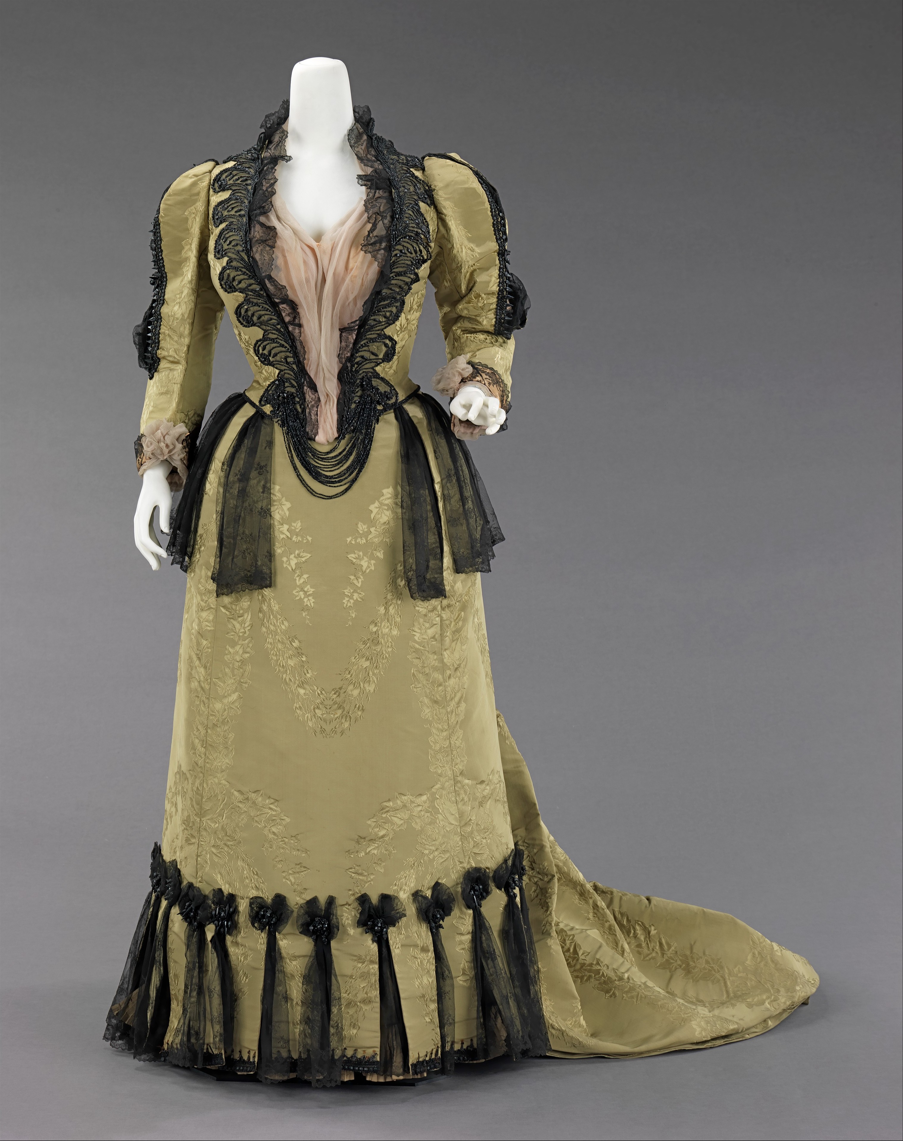 House of Worth ensemble from 1893 in dark silk with jet and metal ornament, shown frontally.