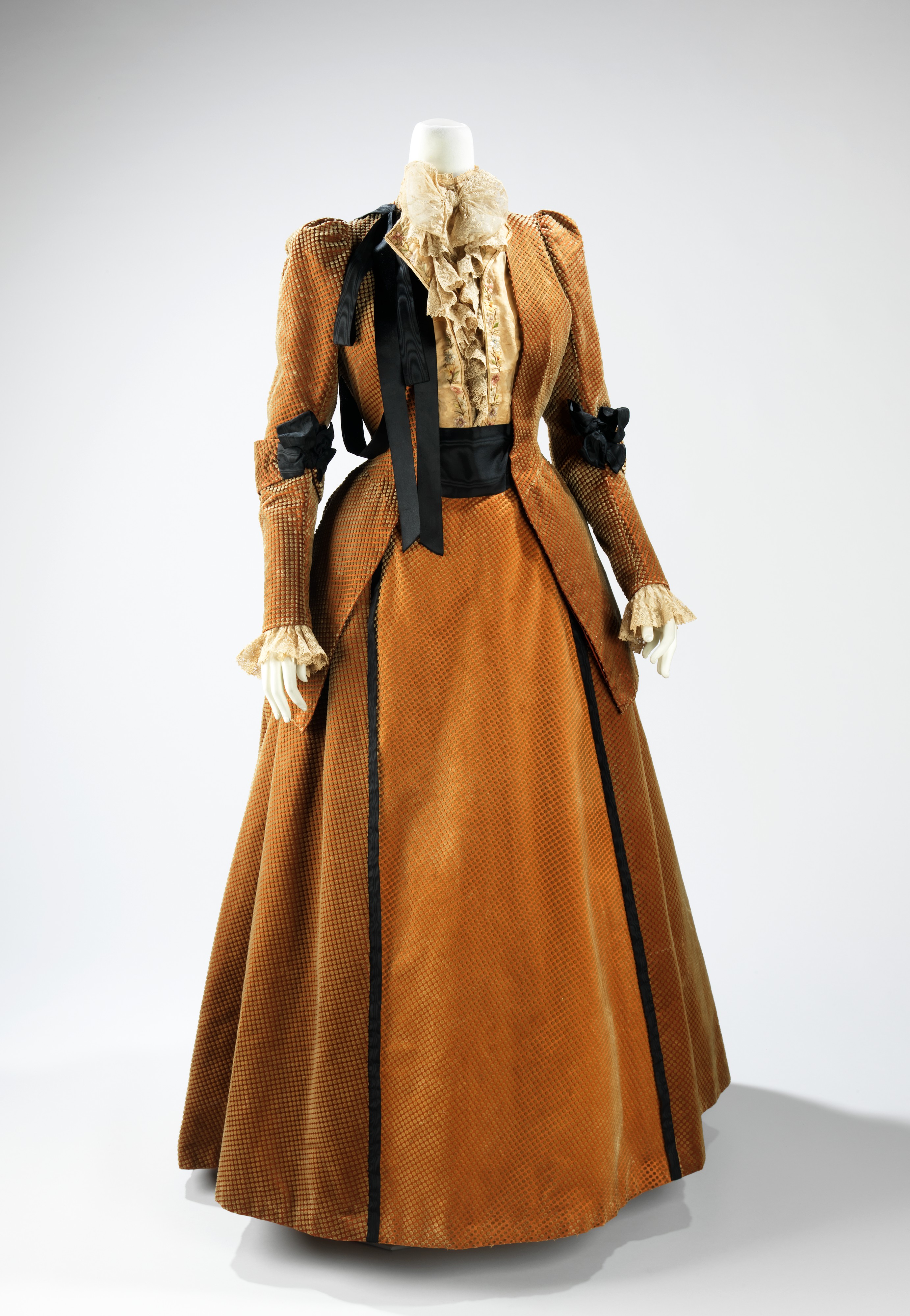 Dark silk House of Worth walking suit from about 1889, photographed frontally against a neutral background.