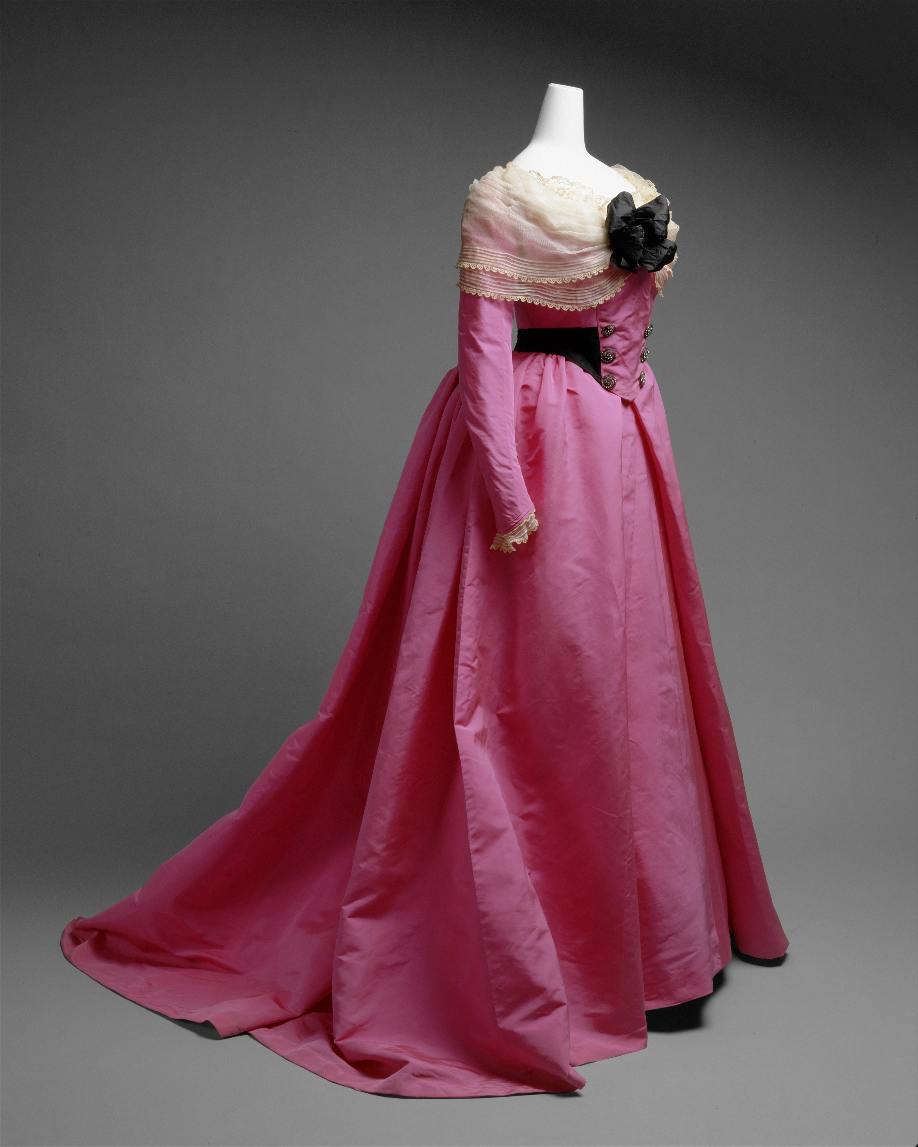 Elaborate House of Worth silk fancy dress costume with a fitted bodice, dark patterned skirt, and dramatic decorative sleeves, around 1893.