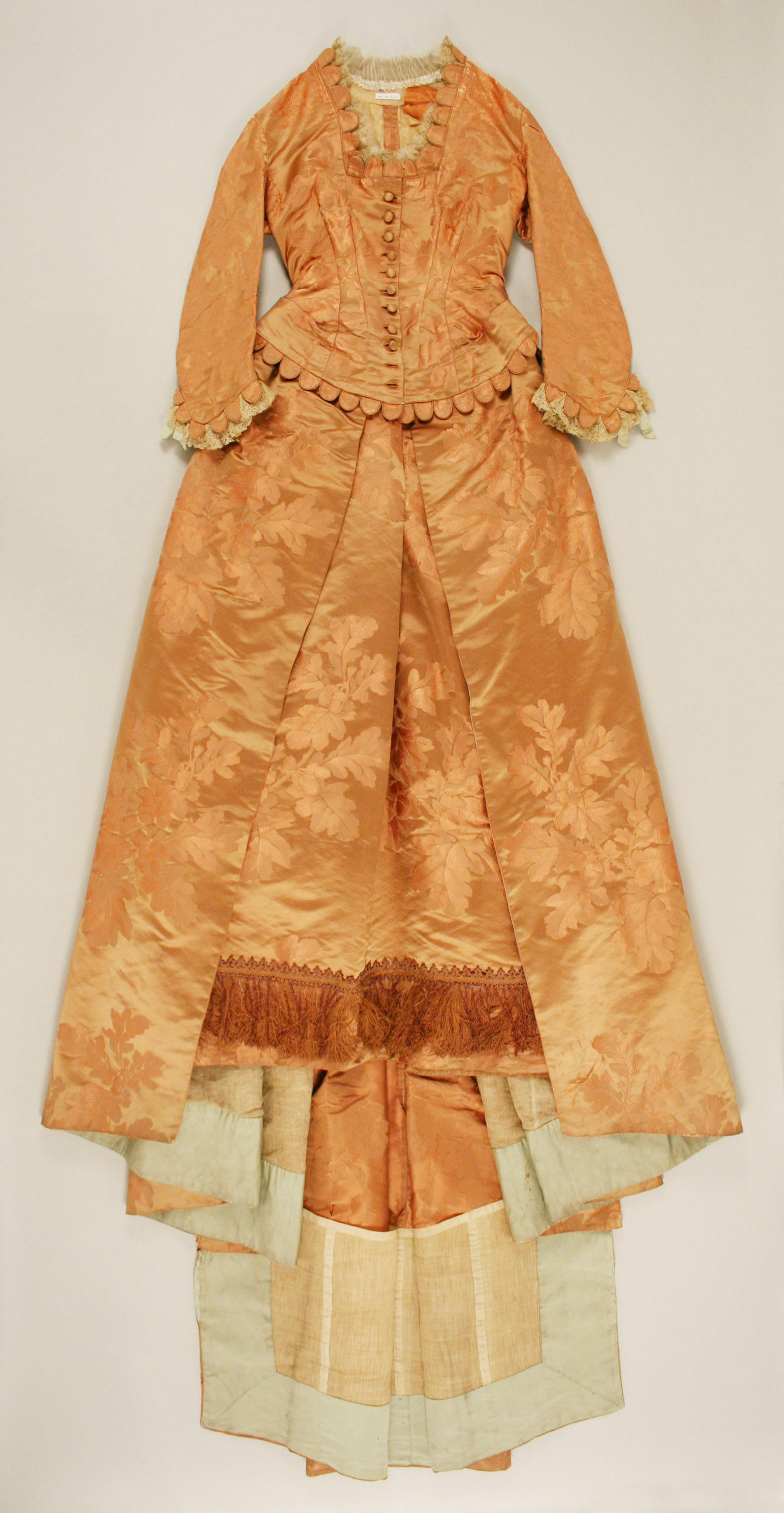 House of Worth silk dinner dress from about 1877, with a fitted bodice and long decorated skirt.