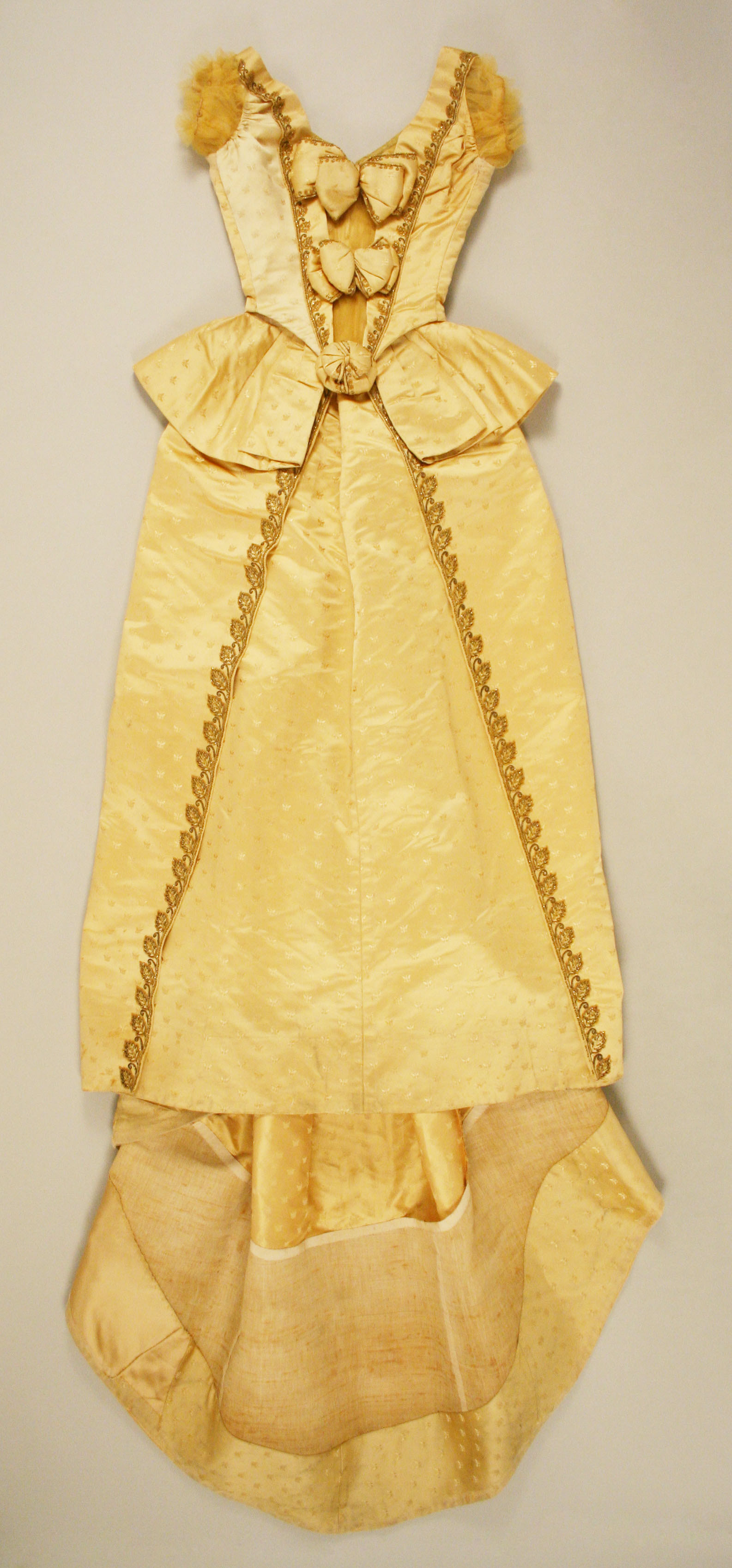 House of Worth ball gown from about 1887, with a structured pale silk silhouette and elaborate surface ornament.